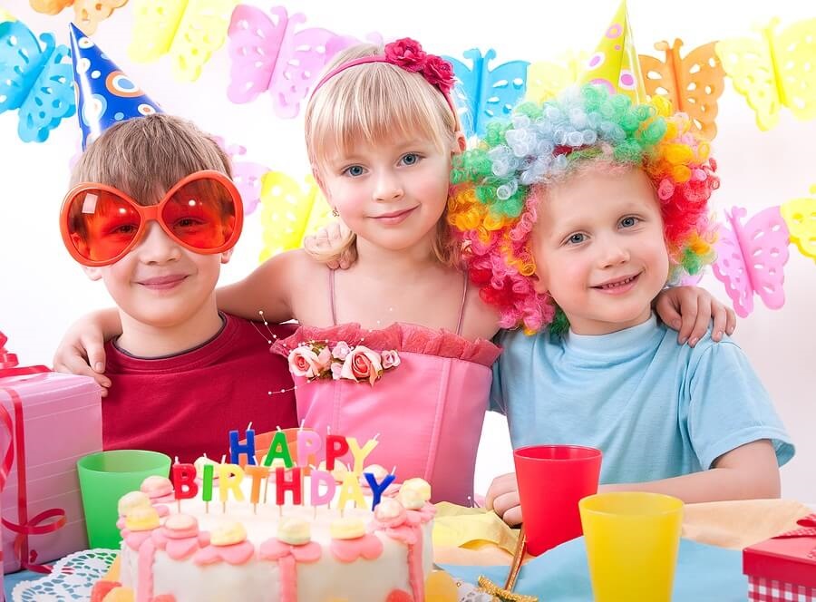 Three kids at birthday party in front of cake